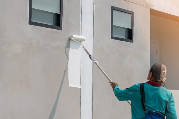 The man paint white color on building wall in the construction site.